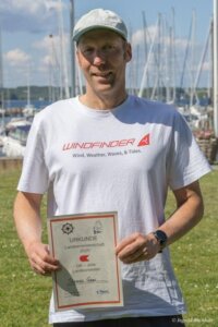 Thomas Glas zeigt seine Urkunde als Landesmeister der OK-Jollen.