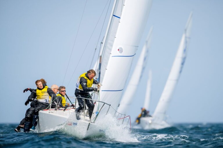 Die Mannschaft auf einem Kielboot bereitet in den Wellen ein Segelmanöver vor.