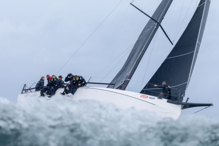 Eine Yacht taucht in die Gischt der Welle ein.
